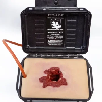 The Gunshot Wound in a Box® is a realistic, compact task trainer designed to teach wound packing for soft-tissue gunshot injuries. Made with durable, UV-resistant silicone and integrated blood tubing, it enables pressure-responsive bleeding when connected to a simulation system. - SÅR-PTT-B01