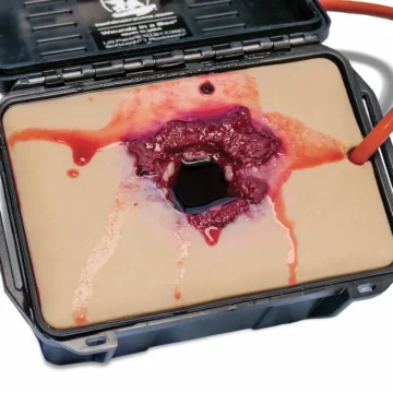 The Gunshot Wound in a Box® is a realistic, compact task trainer designed to teach wound packing for soft-tissue gunshot injuries. Made with durable, UV-resistant silicone and integrated blood tubing, it enables pressure-responsive bleeding when connected to a simulation system. - SÅR-PTT-B01